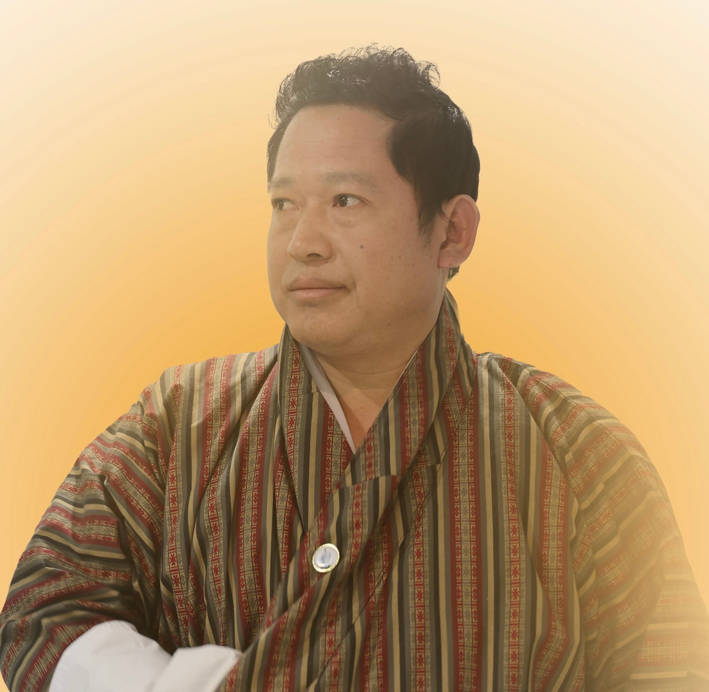 Kencho Tempa in traditional dress in a reflective portrait used on the BWK website.